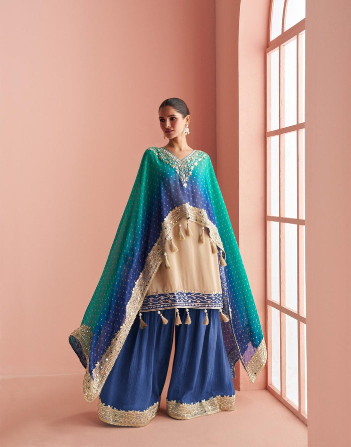 Ivory short kurta with a teal ombre cape drape and flared sharara pants, photographed against a plain backdrop