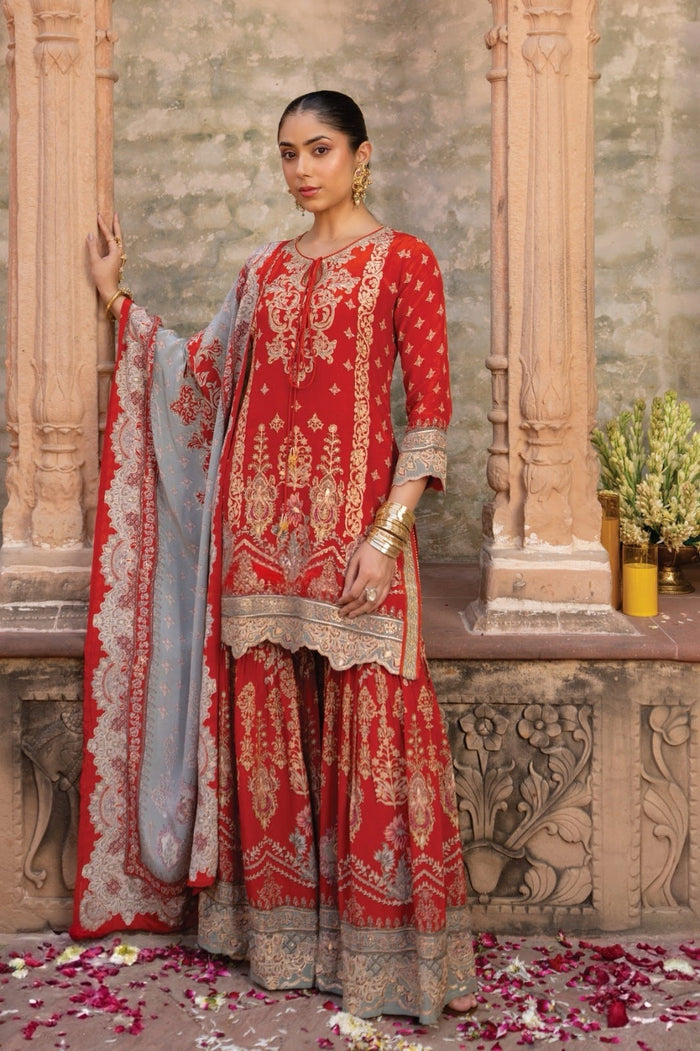 Vermilion red sharara set with antique gold heritage embroidery, worn as a wedding guest outfit