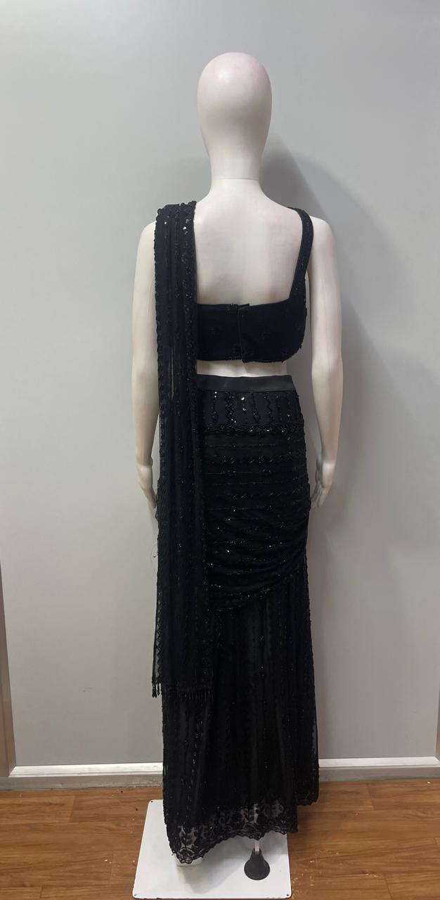 Side view showing the ruched waist and floor-length fall of a black draped skirt