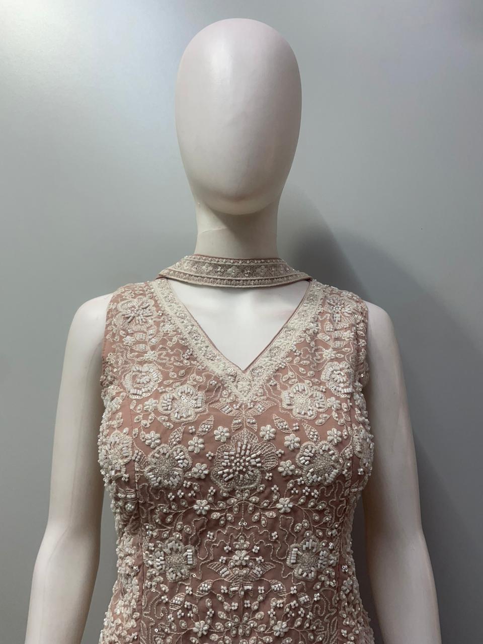 Close view of the pearl beadwork and floral motifs on a dusty rose top