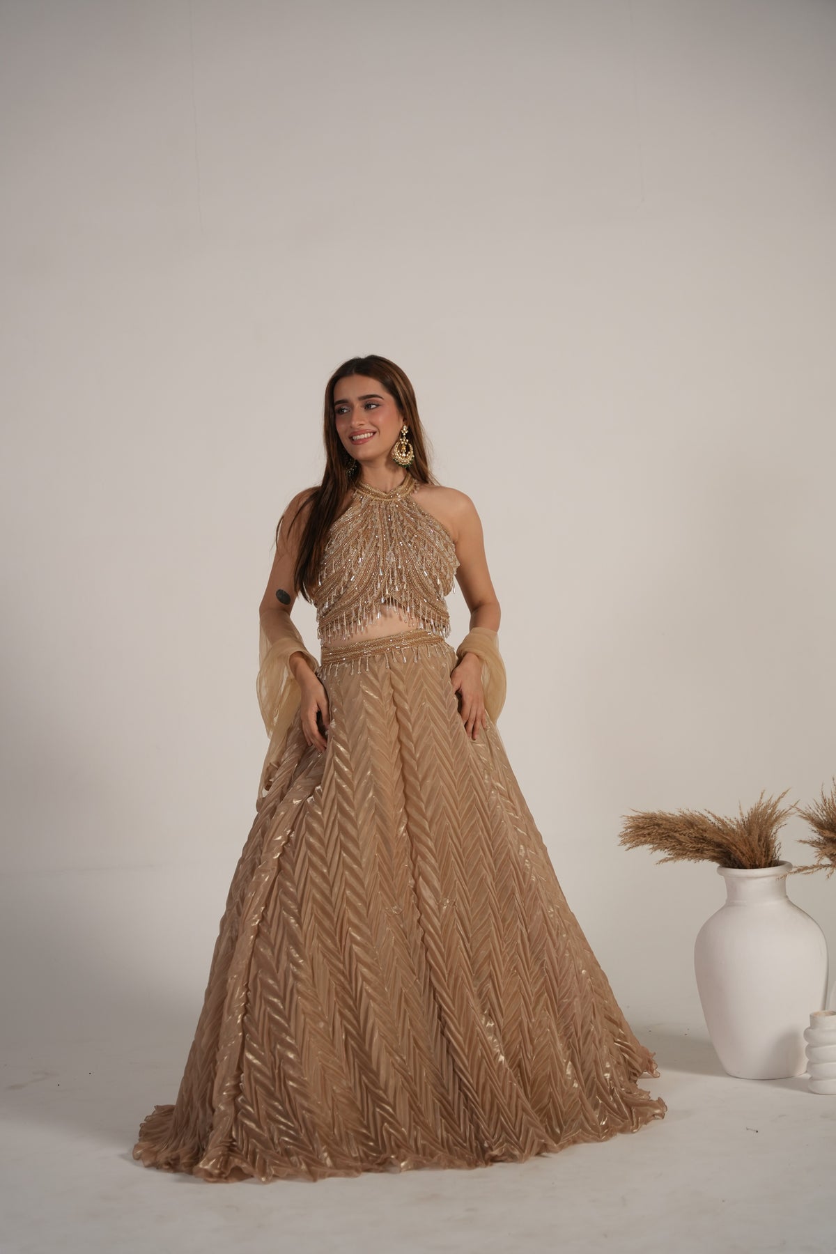 Full-length view of a champagne shimmer halter lehenga ensemble