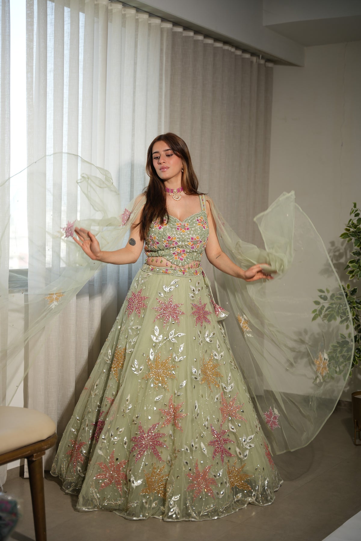 Back view of a sage green floral net lehenga skirt and blouse