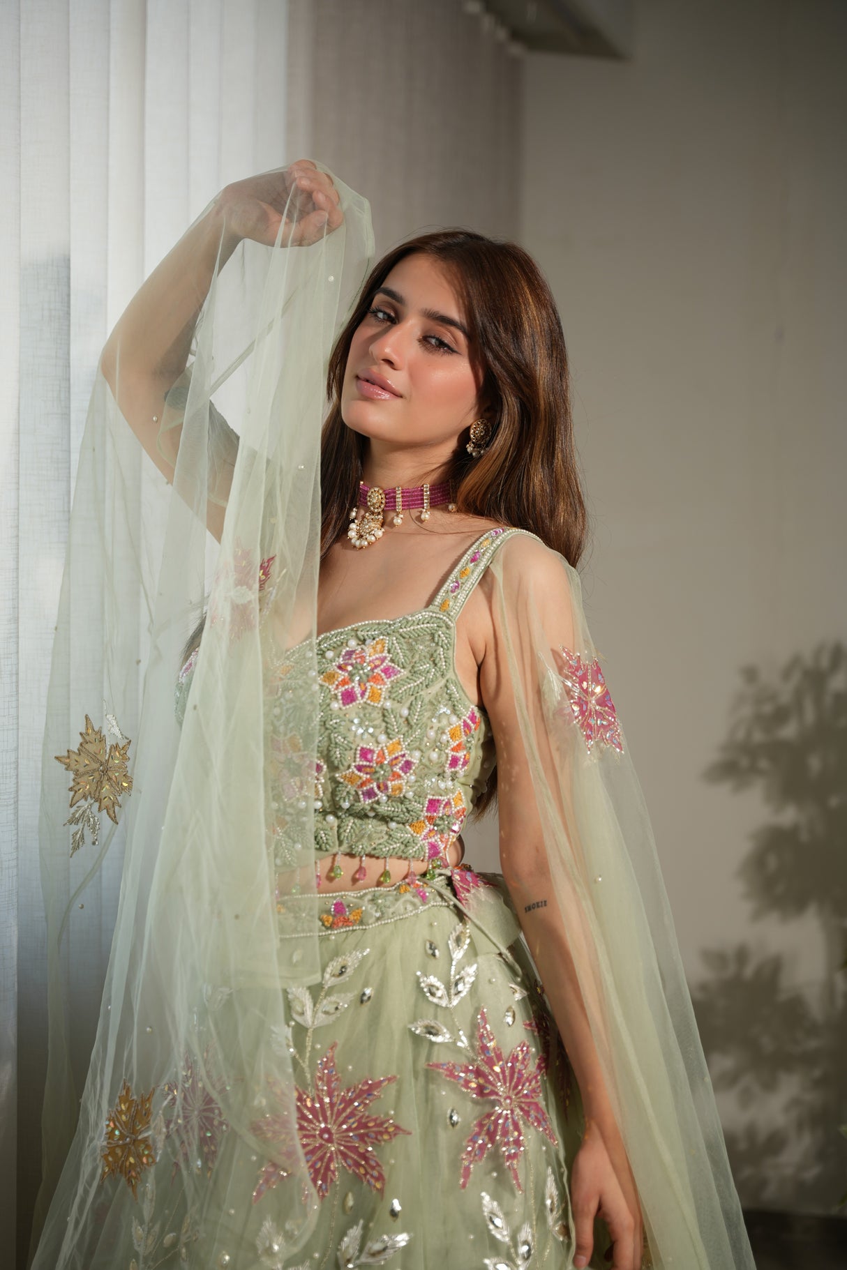 Sage floral net lehenga photographed against a plain backdrop
