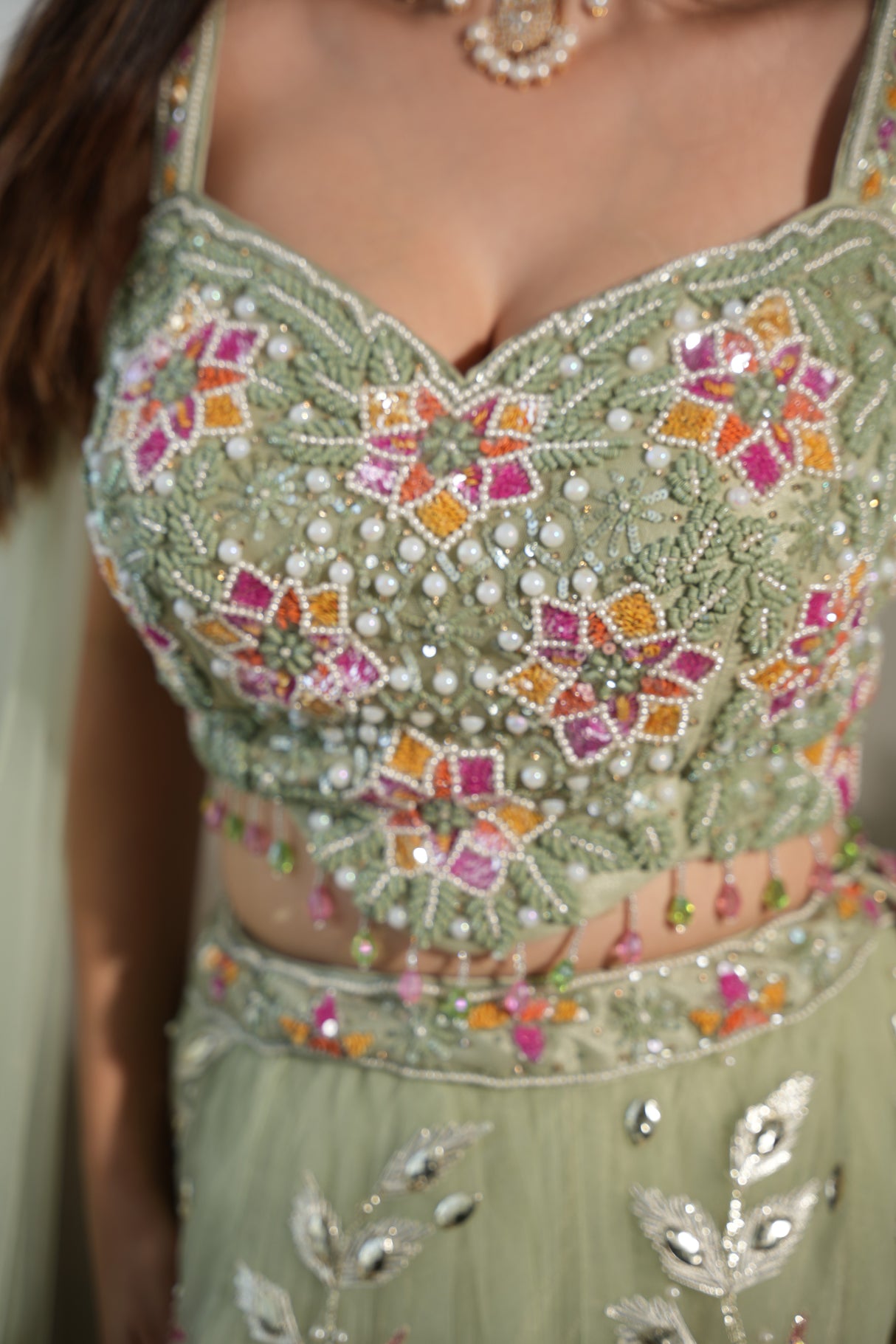 Close view of the floral work on a sage green net lehenga skirt