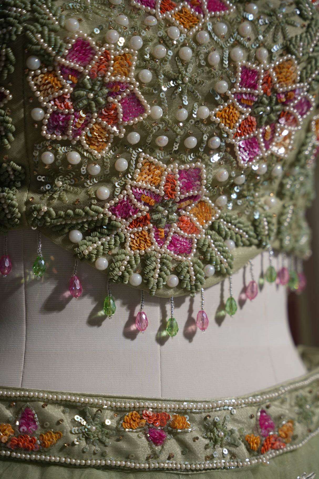 Close view of the net fabric and floral motifs on a sage lehenga