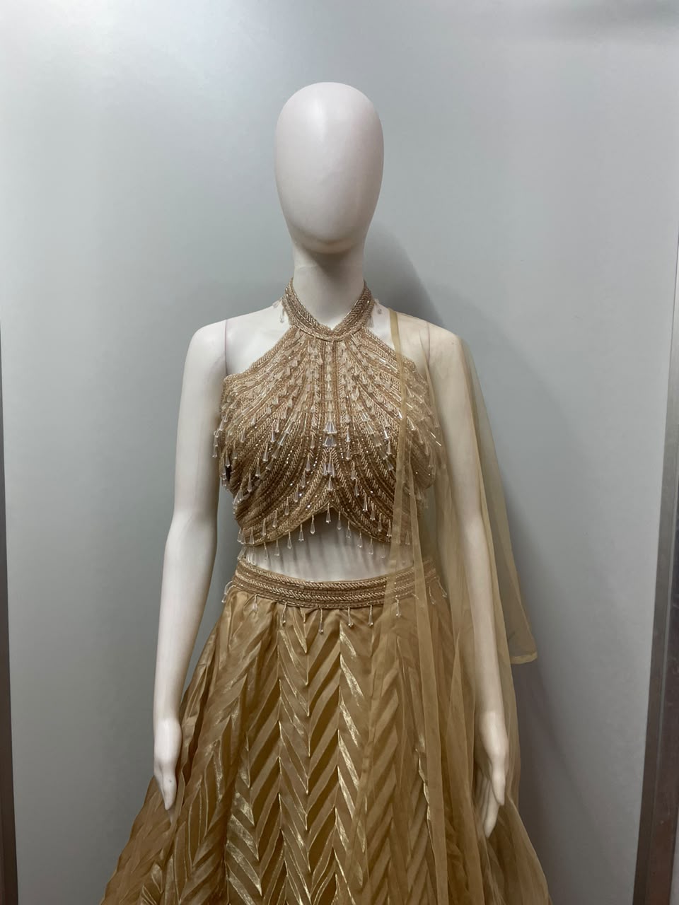 Back view of a champagne shimmer halter lehenga skirt and blouse