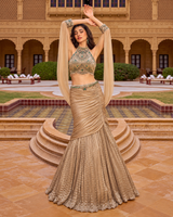 Champagne gold halter blouse with emerald jewel work and a draped lehenga skirt