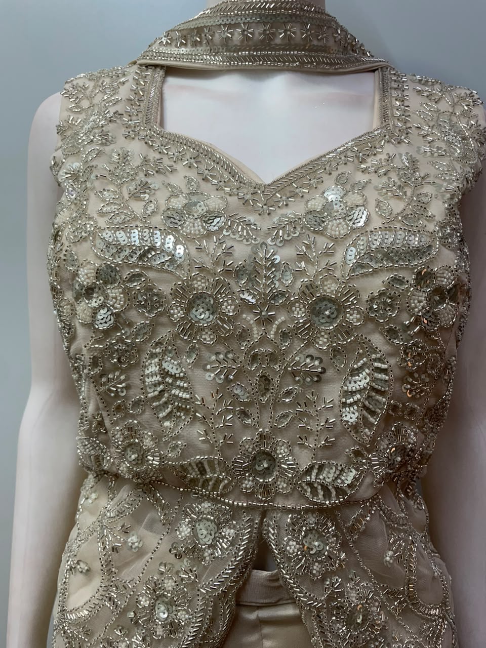 Scalloped hem of the split-front peplum top in champagne gold