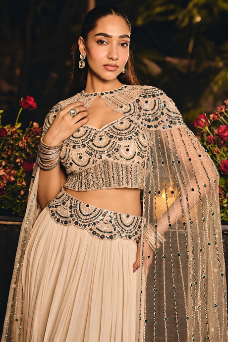 Emerald jewel accents on the sheer floor-length cape of a champagne skirt set