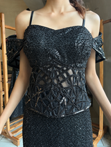 Off-shoulder detail on the sheer corset top of a jet black sequin skirt set
